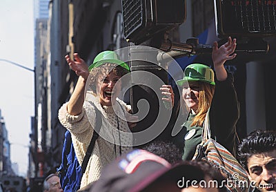 Happy young women with green bowler hats cheering and waving at St. Patrickâ€™s Day parade in the streets. Editorial Stock Photo